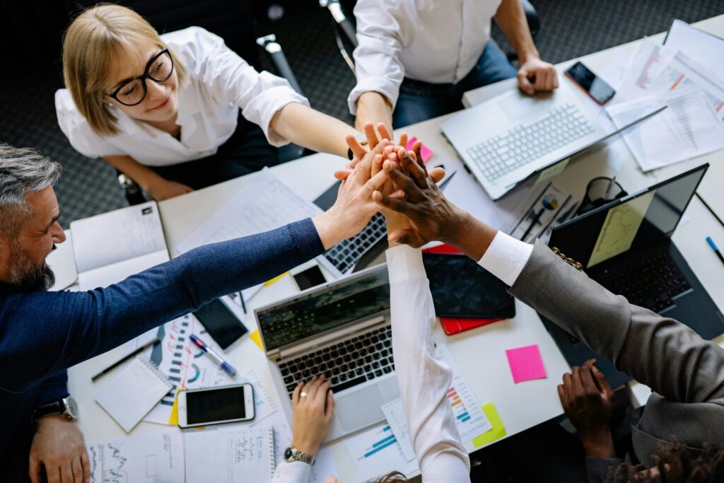 pexels-photo-7793692-7793692 A group of diverse professionals high-fiving over a collaborative workspace.